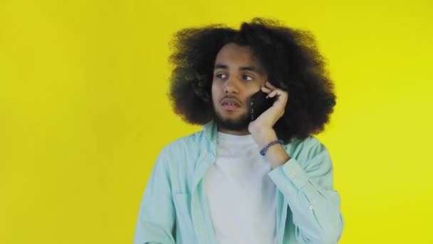 Afro-americano uomo parlando su cellulare mentre in piedi isolato su sfondo giallo — Video Stock