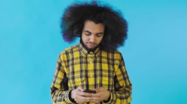 Mavi arka planda telefonu kullanan yakışıklı Afro-Amerikan bir adam. Duyguların kavramı