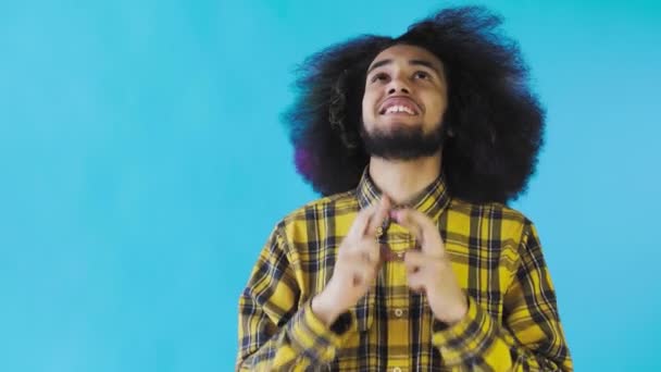 Retrato de un chico afroamericano rezando manteniendo los dedos cruzados y gritando dios por favor sobre fondo azul. Concepto de emociones — Vídeo de stock