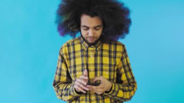 Hüsrana uğramış genç Afro-Amerikan bir adam mavi arka planda kırık cep telefonu tutuyor. Duyguların kavramı
