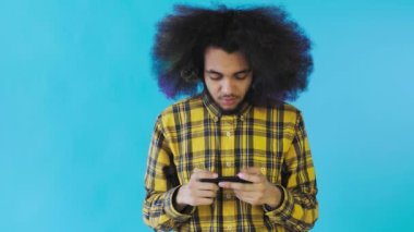 Mavi arka planda Smartphone 'da Afro-Amerikalı Adam Oyun oynuyor. Duyguların kavramı