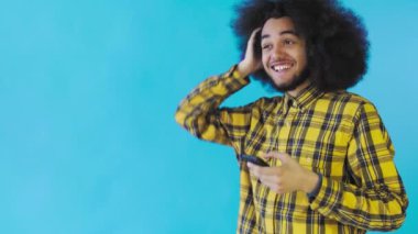 Mutlu çekici Afro-Amerikalı adam telefonu kullanıyor ve Mavi arka planda iyi haberler alıyor. Duyguların kavramı