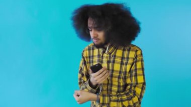 Mavi arka planda kulaklıkla müzik dinlemek için telefonu kullanan Afro-Amerikan bir adam. Duyguların kavramı