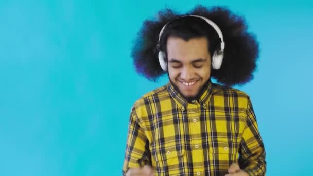 Позитивний афроамериканець, який слухає музику в навушниках на Blue background. Концепція емоцій — стокове відео