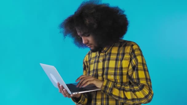 Gelukkige Afro-Amerikaanse man met laptop op blauwe achtergrond. Concept van emoties — Stockvideo