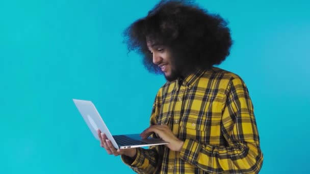 Gelukkige Afro-Amerikaanse man met behulp van laptop, glimlachen en weg te gaan op Blauwe achtergrond. Concept van emoties — Stockvideo