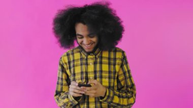 Mor arka planda akıllı telefondan konuşan kıvırcık saçlı Afro-Amerikan bir adamın portresi. Duyguların kavramı