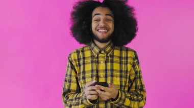 Genç mutlu Afrikalı iş adamı telefonu kullanıyor ve mor arka planda iyi haberler alıyor. Duyguların kavramı