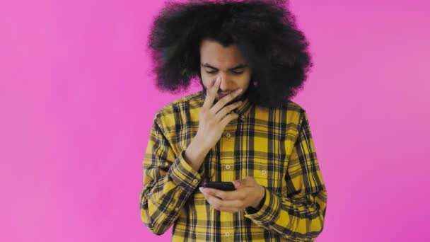 Giovane uomo afro-americano triste utilizzando il telefono e ricevendo cattive notizie su sfondo viola. Concetto di emozioni — Video Stock