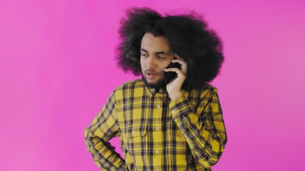 快乐迷人的年轻非洲裔美国人在紫色背景的手机上交谈。情绪的概念 — 图库视频影像