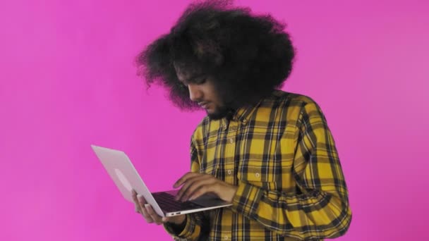 Щасливий афроамериканець, який використовує ноутбук на фіолетовому фоні. Концепція емоцій — стокове відео