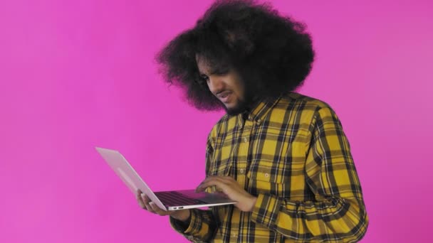 Афроамериканець, який друкує на ноутбуці. Ні, хитаючи головою. На фіолетовому фоні. Концепція емоцій — стокове відео