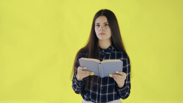 Beautifu tankeväckande flicka läser bok isolerad på gul bakgrund — Stockvideo