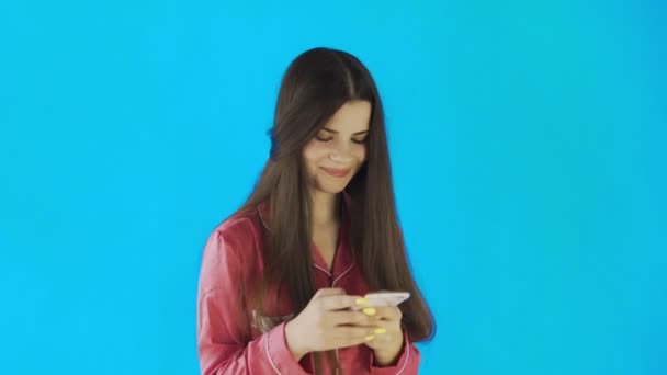 Junge Frau trägt rosa Pyjama mit Handy — Stockvideo