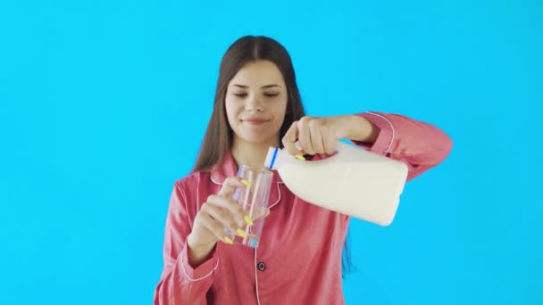 Ελκυστική νεαρή κοπέλα με πιτζάμες πίνει γάλα — Αρχείο Βίντεο