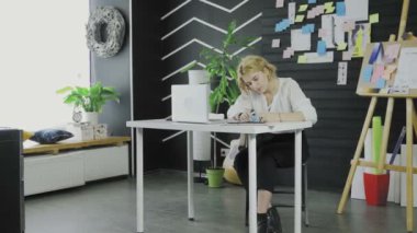 İş kadını masada otururken çıkartmalara bir şeyler yazıyor.