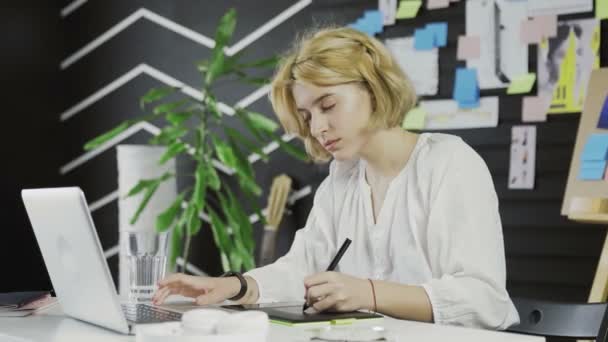 Femme designer travaillant sur un ordinateur portable avec une tablette graphique . — Video