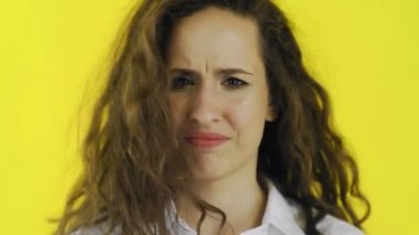 Kameraya bakarken sarı arka planda yalnız duran kızgın genç kadın hayır diyor.