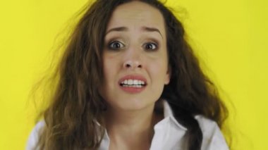 Stüdyoda sarı arka plandaki genç, korkmuş ve korkmuş kadının portresi..