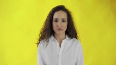 Kendine güveni tam, uzun saçlı bir kadın sarı arka plan için başını sallamadığını söylüyor.