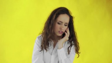 Ciddi bir iş kadını sarı arka planda cep telefonuyla konuşuyor. Stüdyodaki genç iş kadınının portresi. Profesyonel bir kadın akıllı telefondan cep telefonuyla konuşuyor.