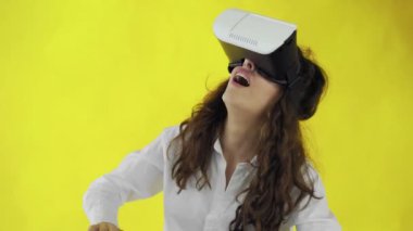 Sanal gerçeklik kulaklığı olan mutlu genç bir kadın mı yoksa stüdyoda sarı arka planda 3D gözlüklü bir kadın mı?.