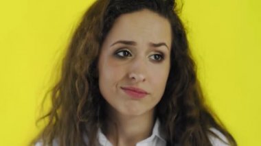 Kafası karışmış güzel beyaz kadın, sarı arka planda duran uzun kahverengi saçlı.