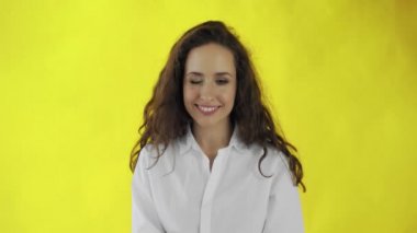 Güzel bir kadın sarı arka planla stüdyoda kırıştırıyor ve flört ediyor..