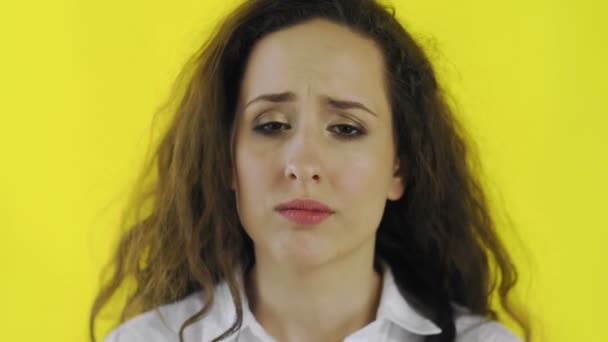 Traurige nachdenkliche junge schöne Frau im Hemd steht im Studio mit gelbem Hintergrund. — Stockvideo