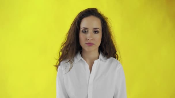 Sério confiante mulher de cabelos longos dizendo sem cabeça tremendo em negação sobre fundo amarelo — Vídeo de Stock