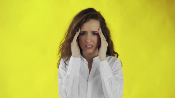Krásná dívka trpí migrénou stojící na žlutém pozadí — Stock video