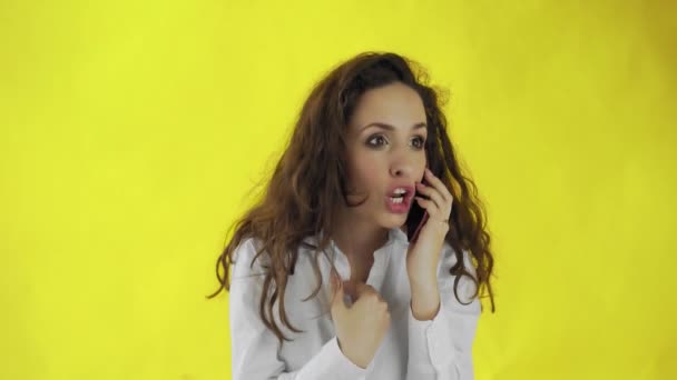 Felice donna in camicia bianca parlando dallo smartphone su sfondo giallo — Video Stock