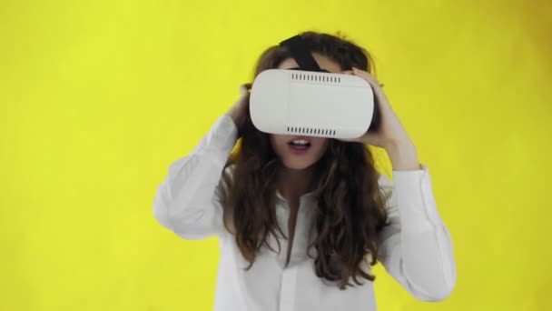 스튜디오의 노란색 배경에 가상 현실 헤드셋을 쓰고 있는 행복 한 젊은 여성 — 비디오