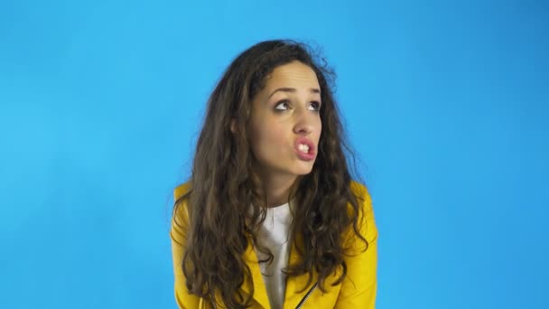 Vážná mladá dospělá žena myšlení a přemýšlivý ve studiu s modrým pozadím. — Stock video