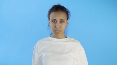 Güzel genç bir kadın mavi arka planda korkunç bir baş ağrısı çekiyor.