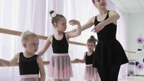 Guru menunjukkan bagaimana menari untuk balerina kecil. Gadis penari di sekolah balet belajar menari. Balerina muda melompat dalam pelatihan. Sekolah balet. — Stok Video