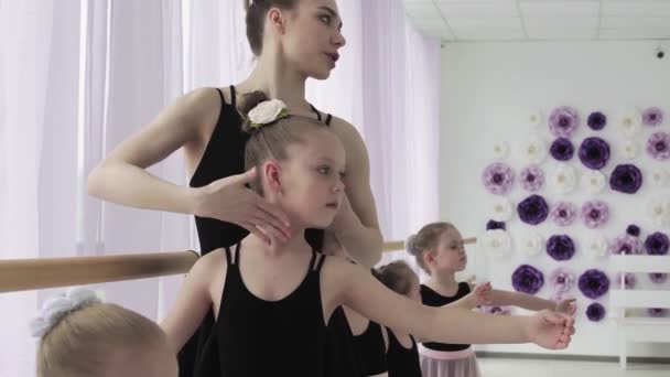 Dívčí tanečnice na baletní škole se učí tancovat. Půvabné dívky v černých a růžových oblecích tančí balet na pozadí panoramatického okna ve studiu. — Stock video