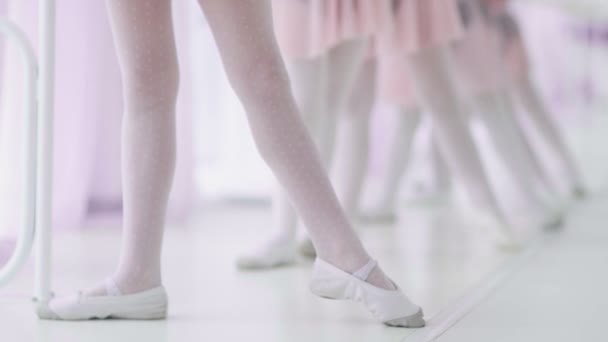 Sluit de voeten van onherkenbare kleine meisjes in witte sokken en balletschoenen, hun balletleraar corrigeert ze — Stockvideo