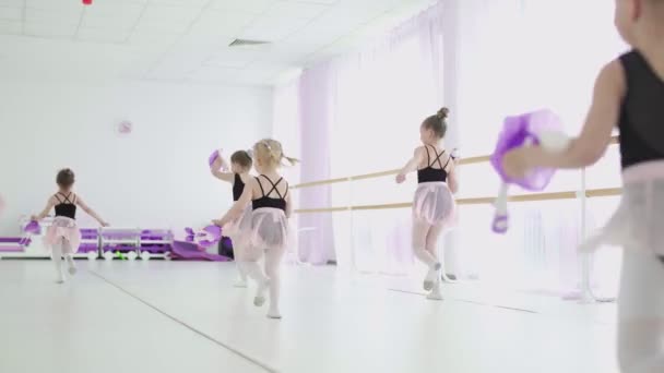 Les petites filles avec des jouets dans les mains courent dans la salle de classe de ballet — Video