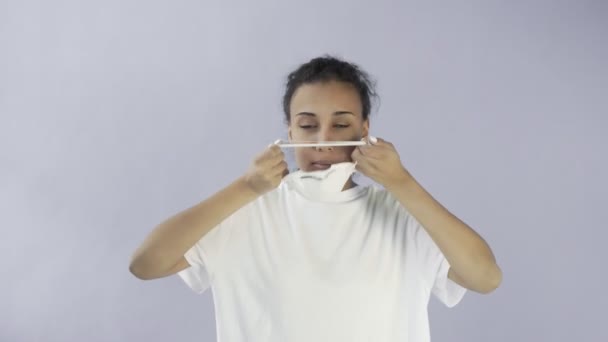 Ung afro-amerikansk flicka bär ansiktsmask på grå bakgrund — Stockvideo