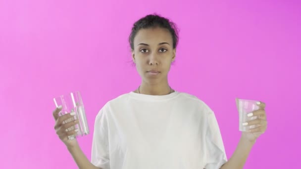 アフリカ系アメリカ人の女の子の活動家ピンクの背景にプラスチックとガラスのカップ — ストック動画