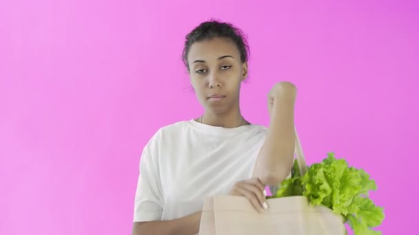 Activista afroamericana con copas de plástico y vidrio sobre fondo rosa — Vídeo de stock