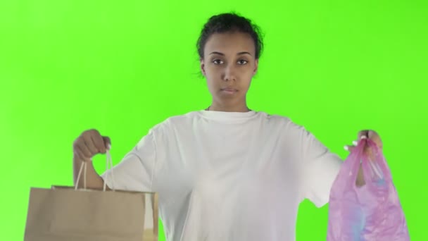 Activista afroamericana haciendo una elección entre papel y bolsa de plástico sobre fondo de croma key — Vídeos de Stock