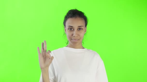 CuteAfro-American Girl está mostrando ok com dois polegares e sorrindo no croma chave fundo no estúdio — Vídeo de Stock