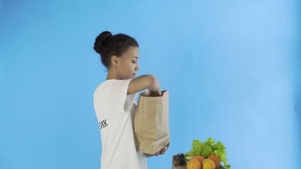 Ευτυχισμένη γυναίκα φορτίο χαρτοσακούλα με βιολογικά υγιεινά λαχανικά και φρούτα — Αρχείο Βίντεο
