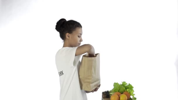 Gelukkig vrouw laden papieren zak met biologische gezonde groenten en fruit op witte achtergrond — Stockvideo