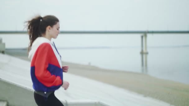 Hermosa mujer en forma usando ropa deportiva corriendo abajo de la calle trotando — Vídeos de Stock
