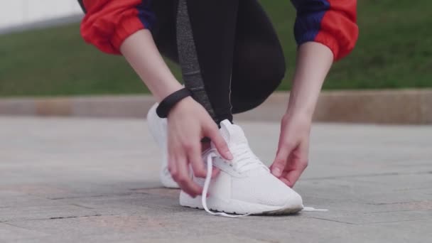 Молодая спортивная женщина завязывает шнурки и бегает — стоковое видео