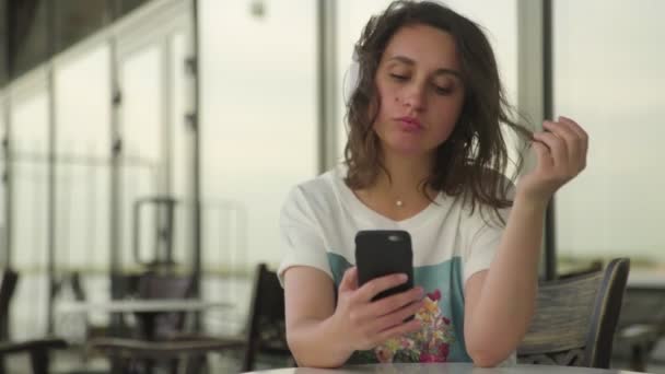 Mujer joven en auriculares mirando el teléfono inteligente — Vídeos de Stock