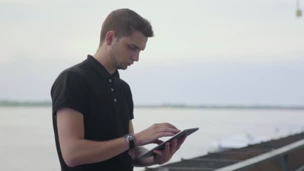 Jovem empresário usando tablet PC fora perto do rio — Vídeo de Stock